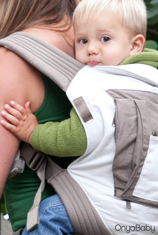 Woman demonstrating how to use an Onya Baby carrier in the back carry position while pregnant.