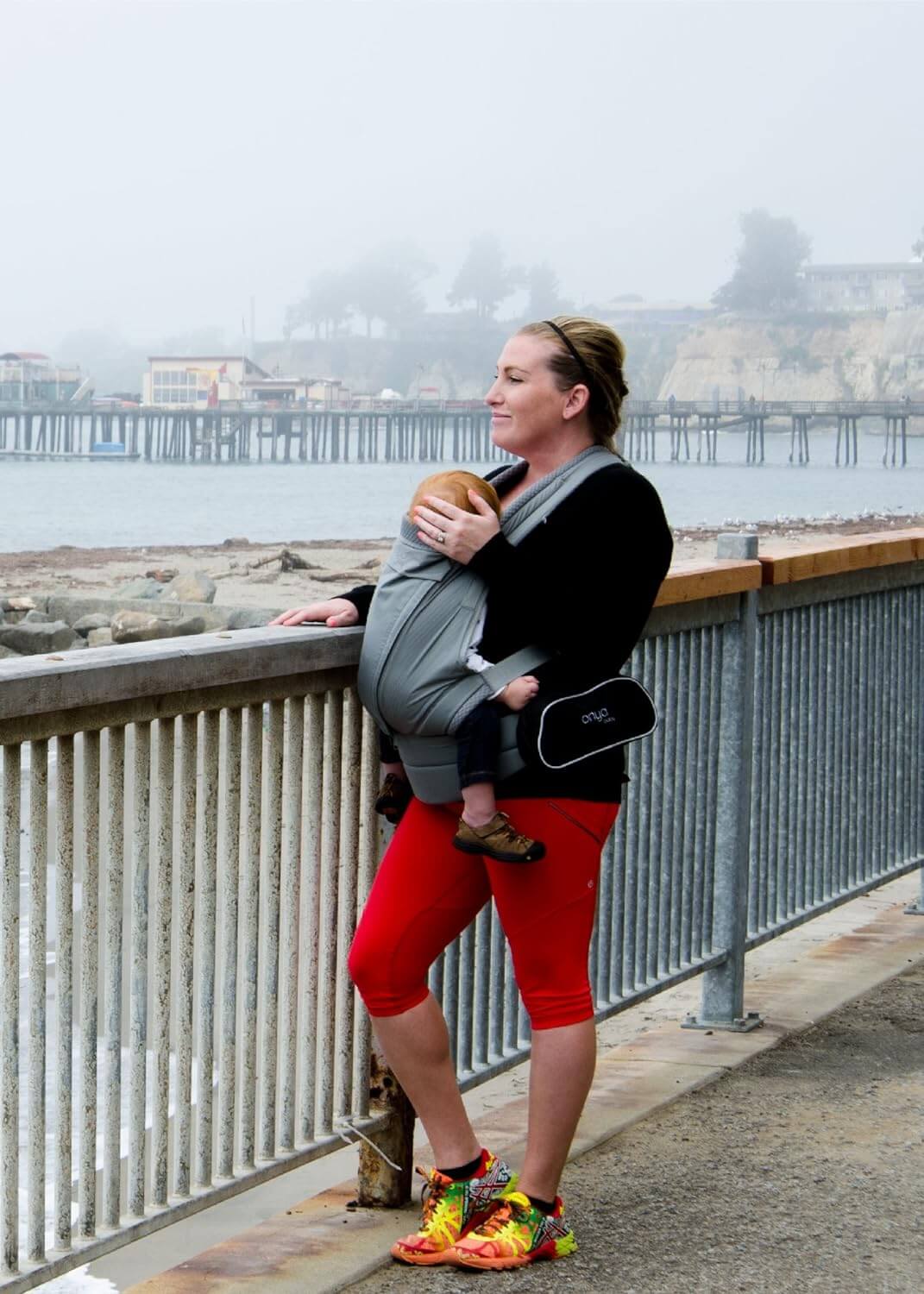 Woman looking at beach wearing a Hipster Bag on the Pure Carrier by Onya Baby with baby in the front carry position