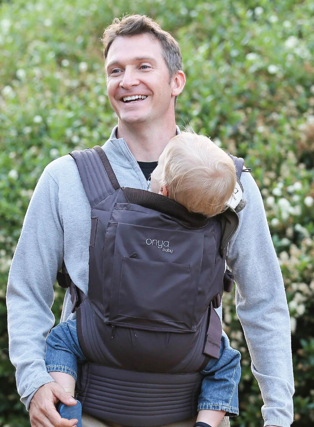 Man walking and carrying child in an Onya Baby Nexstep in the front carry position