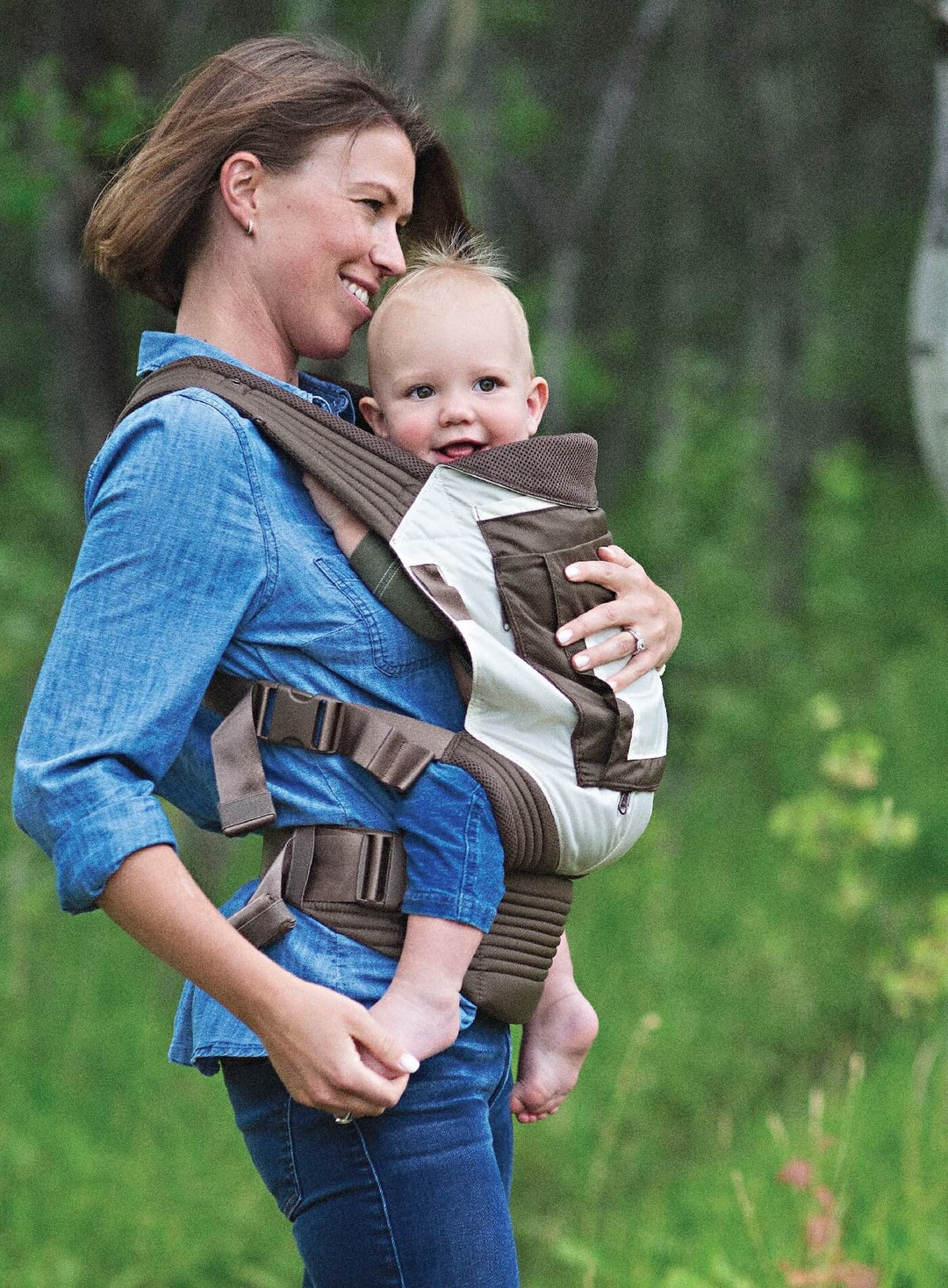 Smiling woman walking and carrying child in an Onya Baby Outback in the front carry position